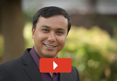 Head shot of Asim with play button overlaid.