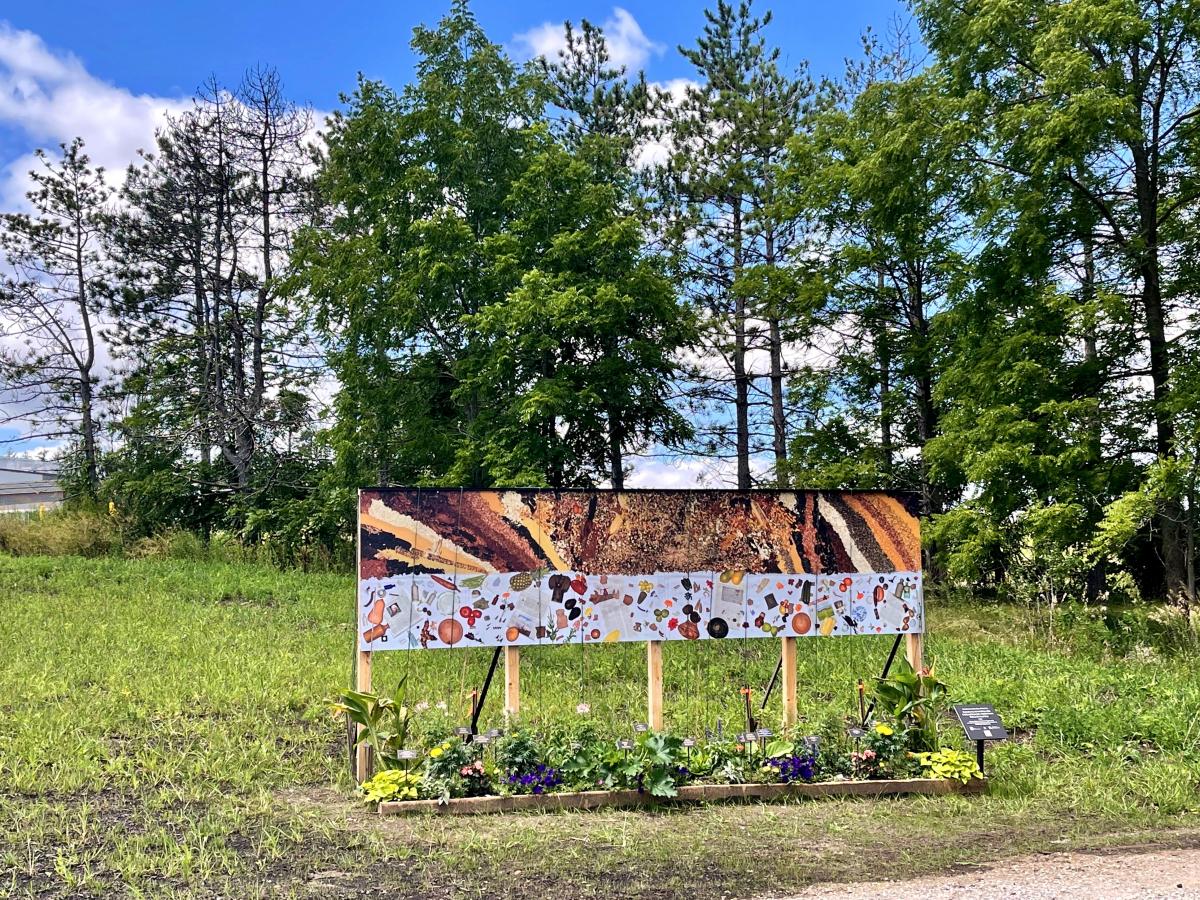 Picture of the art installation. You see a planter filled with plants, and an artistic banner. 