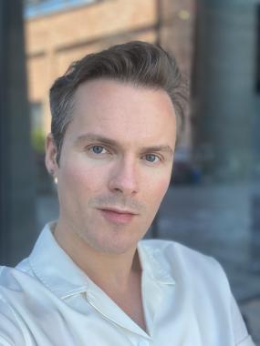 Headshot of Dr. Paul Meighan wearing a white shirt and looking at the camera